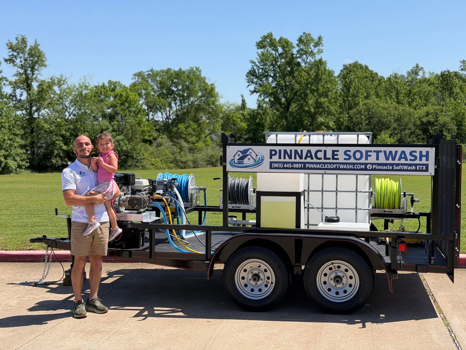 Pinnacle SoftWash owner holding his daughter next to the Pinnacle SoftWash wash trailer